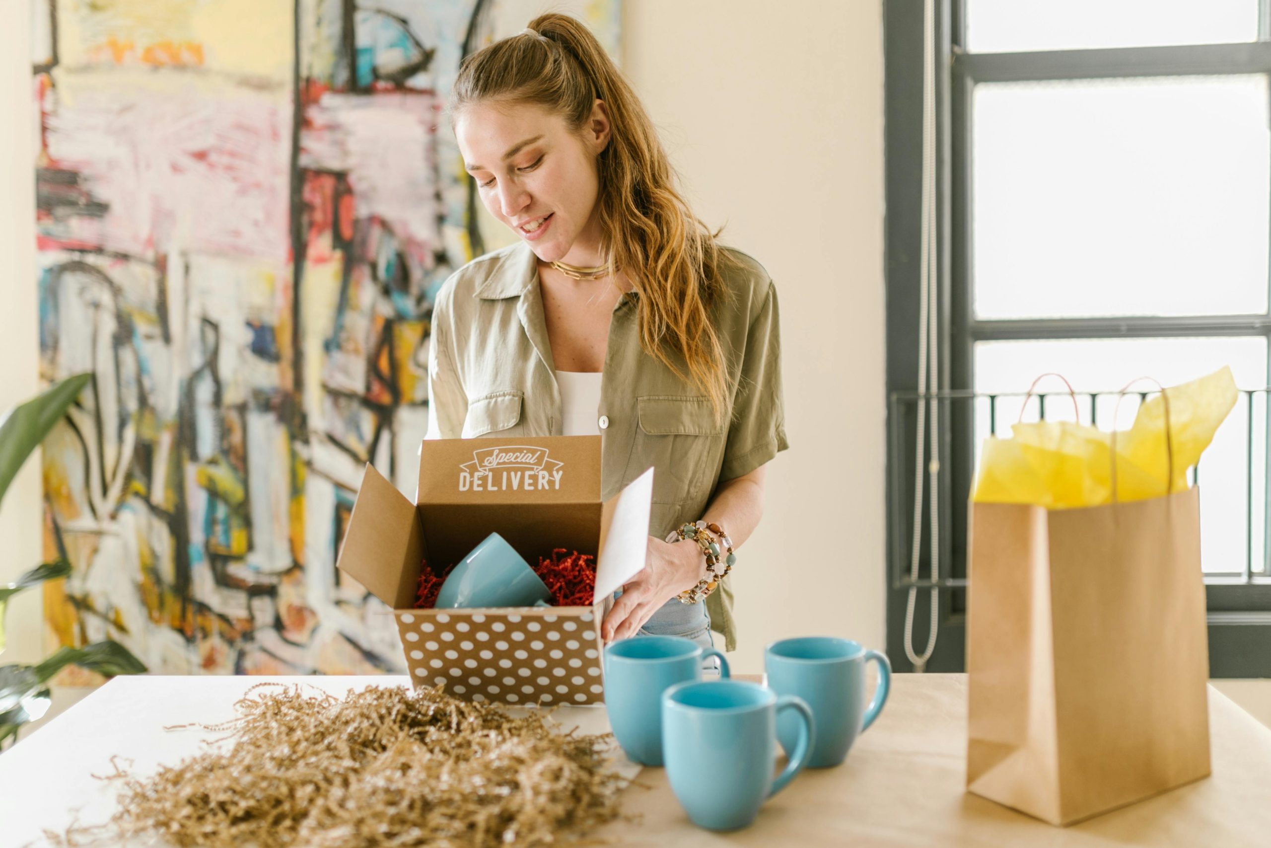femme ouvrant un colis qui contient des mugs goodies