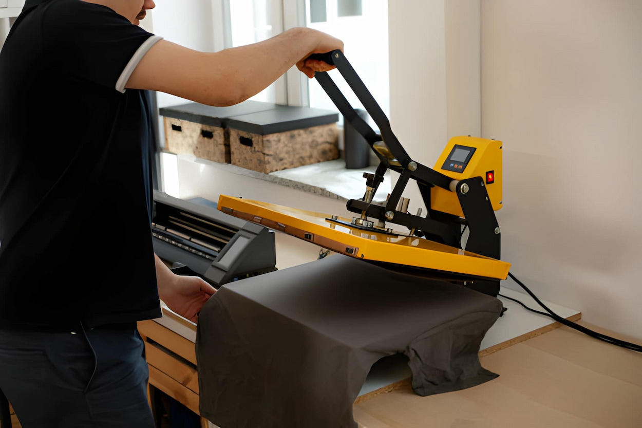 Presse à chaud manuelle appliquant un transfert sur t-shirt pour personnalisation textile – technique transfert thermique pour goodies publicitaires.